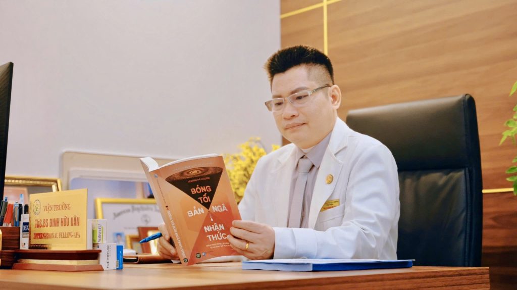 Thạc sĩ, Bác sĩ Đinh Hữu Uân đeo kính, chăm chú đọc sách nghiên cứu tâm lý học tại phòng làm việc.